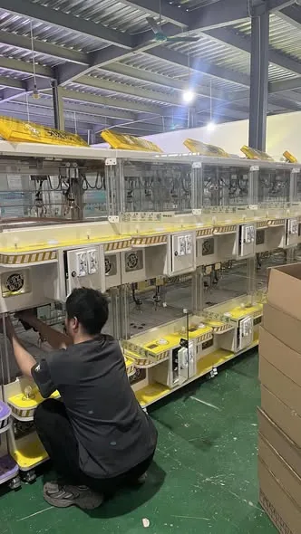 Technician inspecting a claw machine on the assembly line during quality control testing