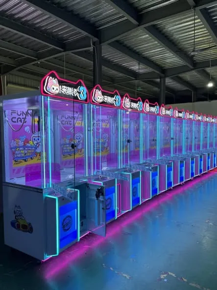 Blue and pink commercial claw machines lined up in a factory showroom ready for shipment