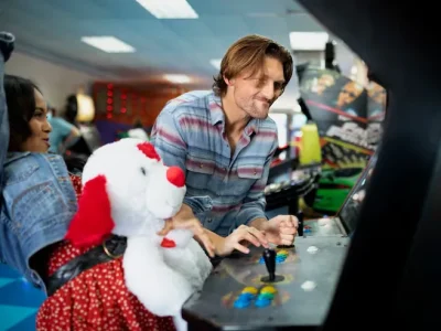 Happy players pointing at a prize inside a claw machine, demonstrating the strategic observation that skilled players use