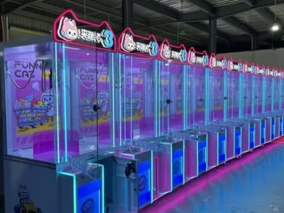 Blue and pink commercial claw machines lined up in a factory showroom ready for shipment